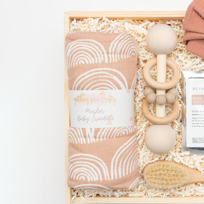 Celebrate the arrival of a new baby with this modern, elegant and practical gift box. Close up of Swaddle Blanket and Natural Wood Rattle