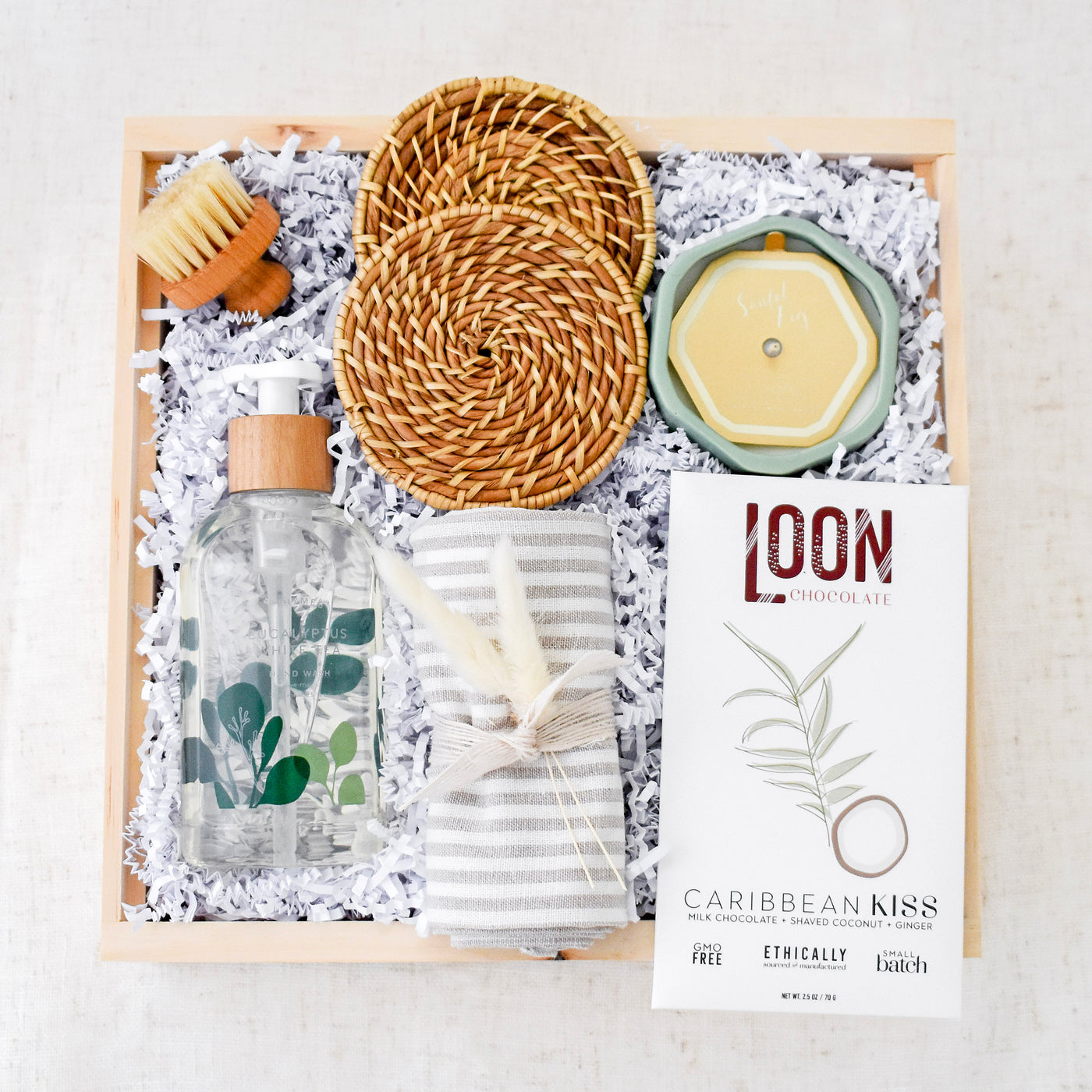 Help new home dwellers settle in with this beautifully refreshing gift box. Includes: Santal Fig Candle, Eucalyptus White Tea Hand Wash, Striped Linen Tea Towel, Caribbean Kiss Chocolate Bar, Rattan Coasters, Mini Scrub Brush 