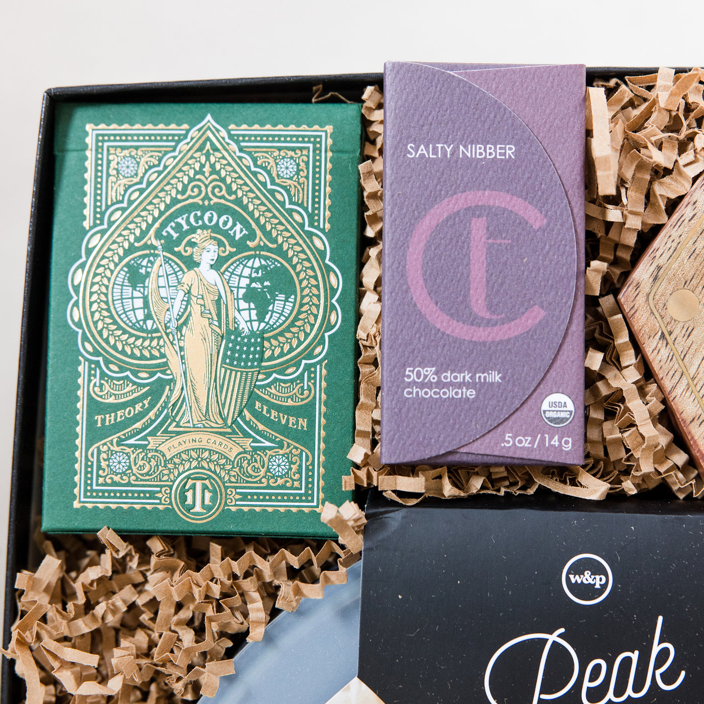 A clever and playful gift to help foster connection at home. This gift box includes all the makings of an amazing game night! Close up of Deck of Playing Cards and Chocolate Dark Salty Nibber