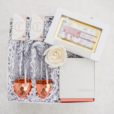 Spread the love with this decadent and romantic gift box. Perfect for weddings, anniversaries or just because! Includes: 2 Coffee and Cream Mini Chocolate Bars, Instant Champagne Sugar Cube Cocktail Kit, Hammered Copper Stemless Champagne Glasses, Coconut Milk Mango Candle